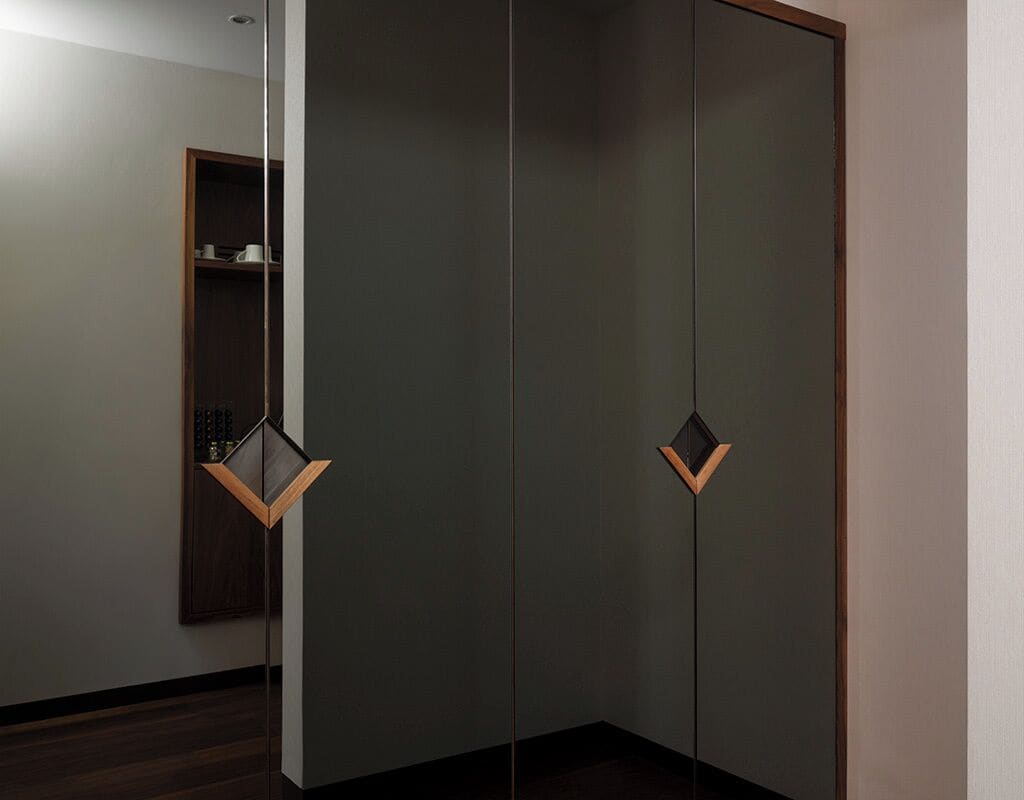 A modern room with a wardrobe, a small shelf with cups, and a wooden floor.