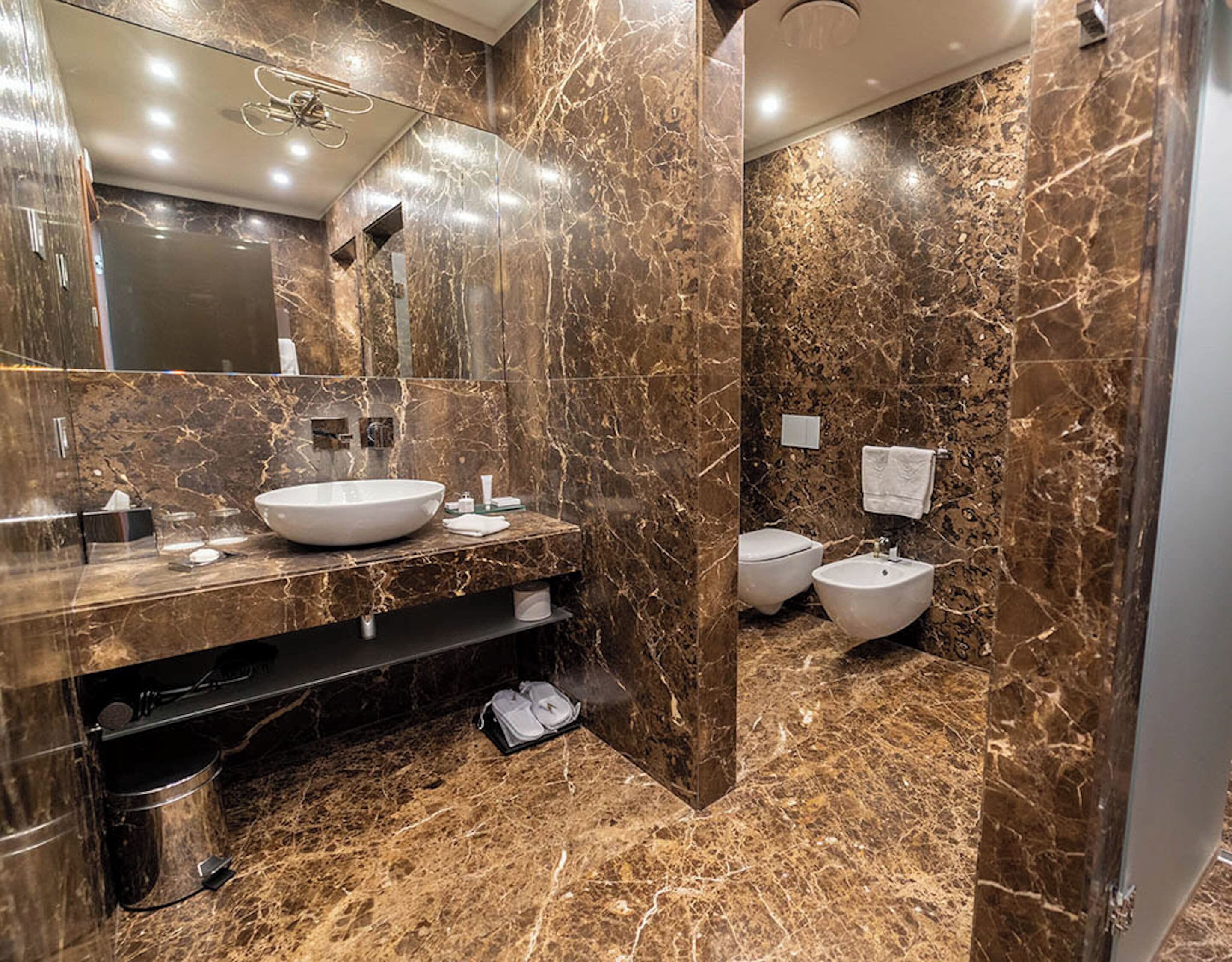 A modern bathroom with a large sink, two toilets, and a mirror.