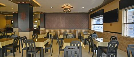 A restaurant with booths and tables, a chandelier, and a patterned wall.