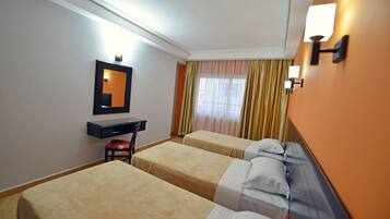 Habitación de hotel con dos camas individuales, un escritorio, una silla, un espejo y una ventana con cortinas.