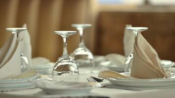 Une table dressée avec de l’argenterie, de la vaisselle blanche et de la verrerie transparente.