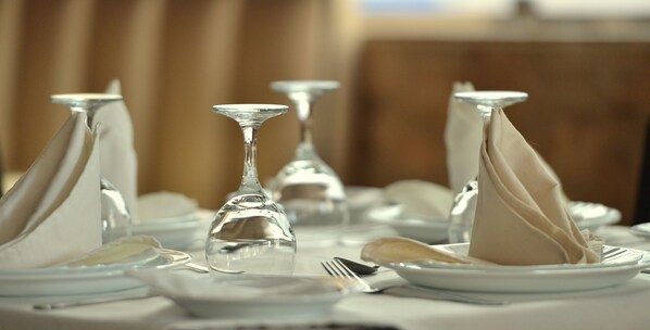A table set with white plates, silverware, and clear glassware.