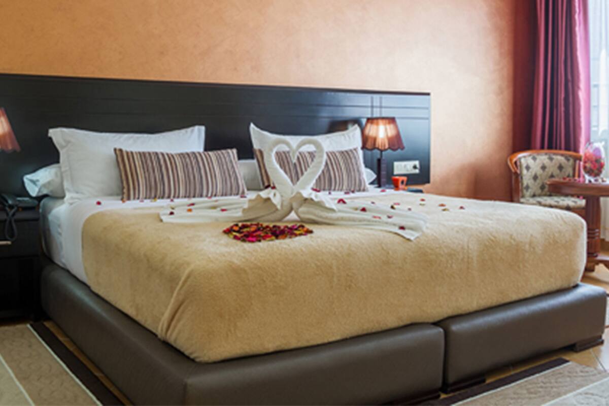 A hotel room with a large bed, a nightstand, a lamp, and a chair.