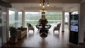 Amplia habitación con un ventanal grande, un candelabro, una mesa de comedor con sillas y una planta en maceta.