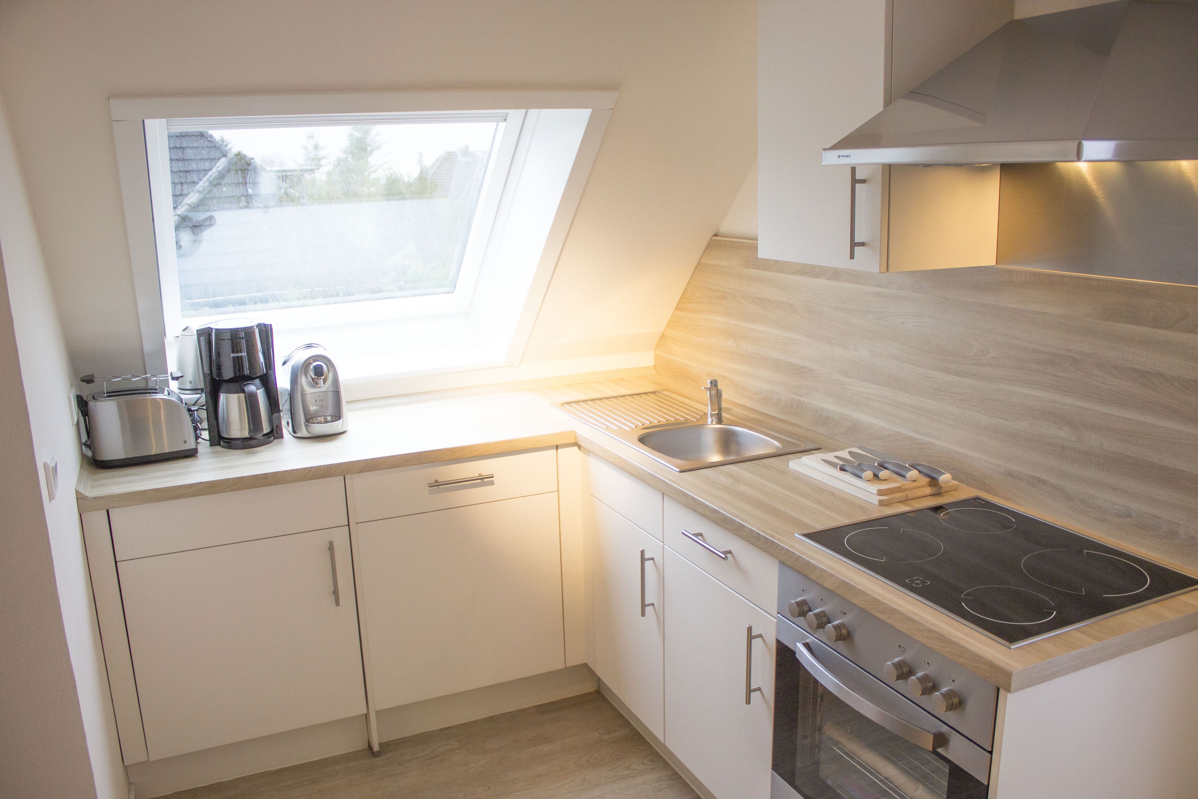 A modern kitchen with a skylight, stainless steel appliances, and wooden countertops.