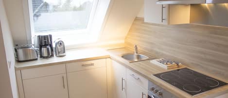 A modern kitchen with a skylight, stainless steel appliances, and wooden countertops.