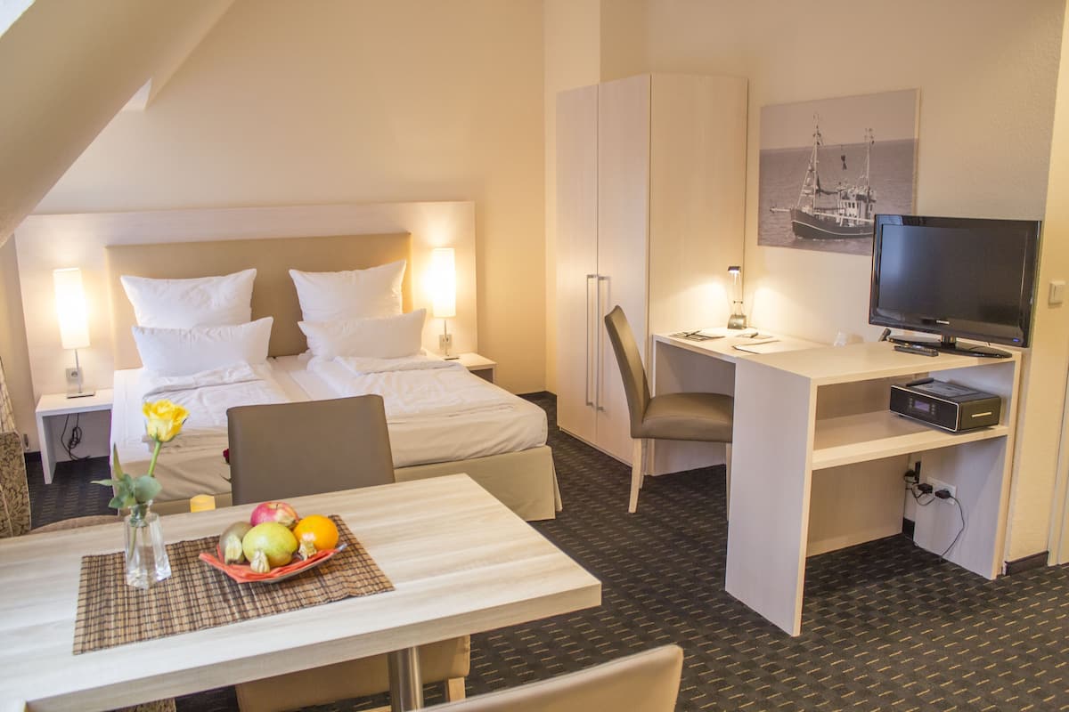 Een hotelkamer met een bed, bureau, stoel, televisie en een fruitmand.