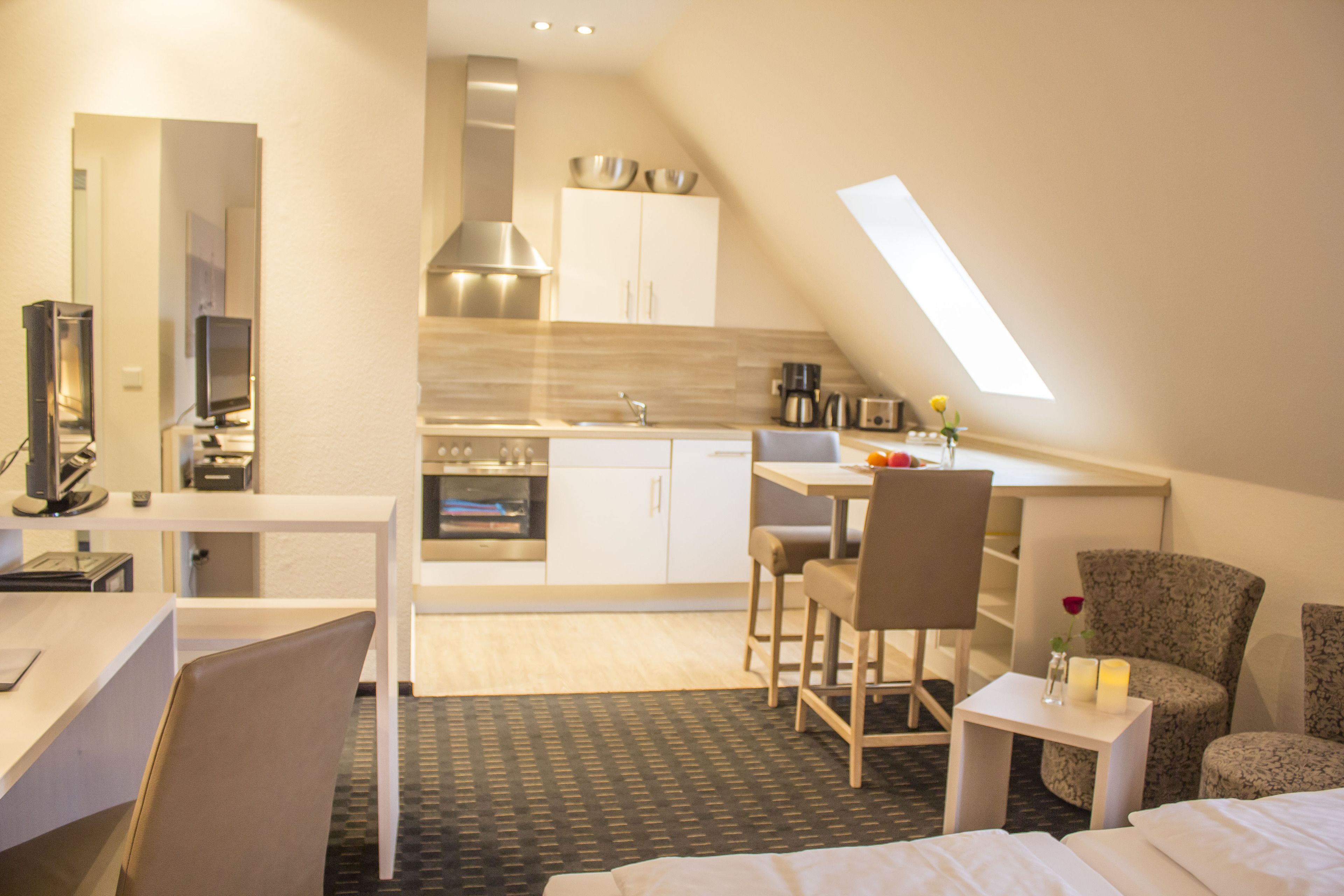 A compact hotel room with a kitchenette, a dining area, and a bedroom.