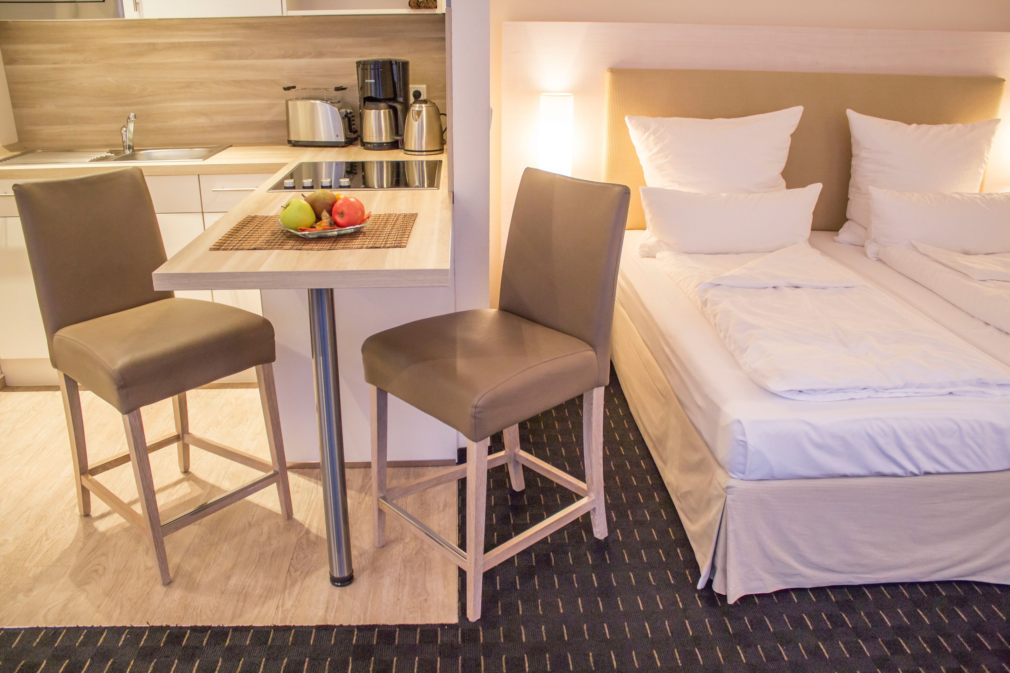Een hotelkamer met een bed, een klein kitchenette en twee stoelen.