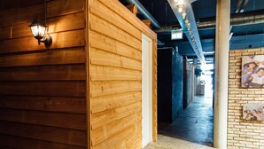 A corridor with wooden panel walls, a hanging lantern, and a brick wall with a framed picture. - ClinkMama (Amsterdam)