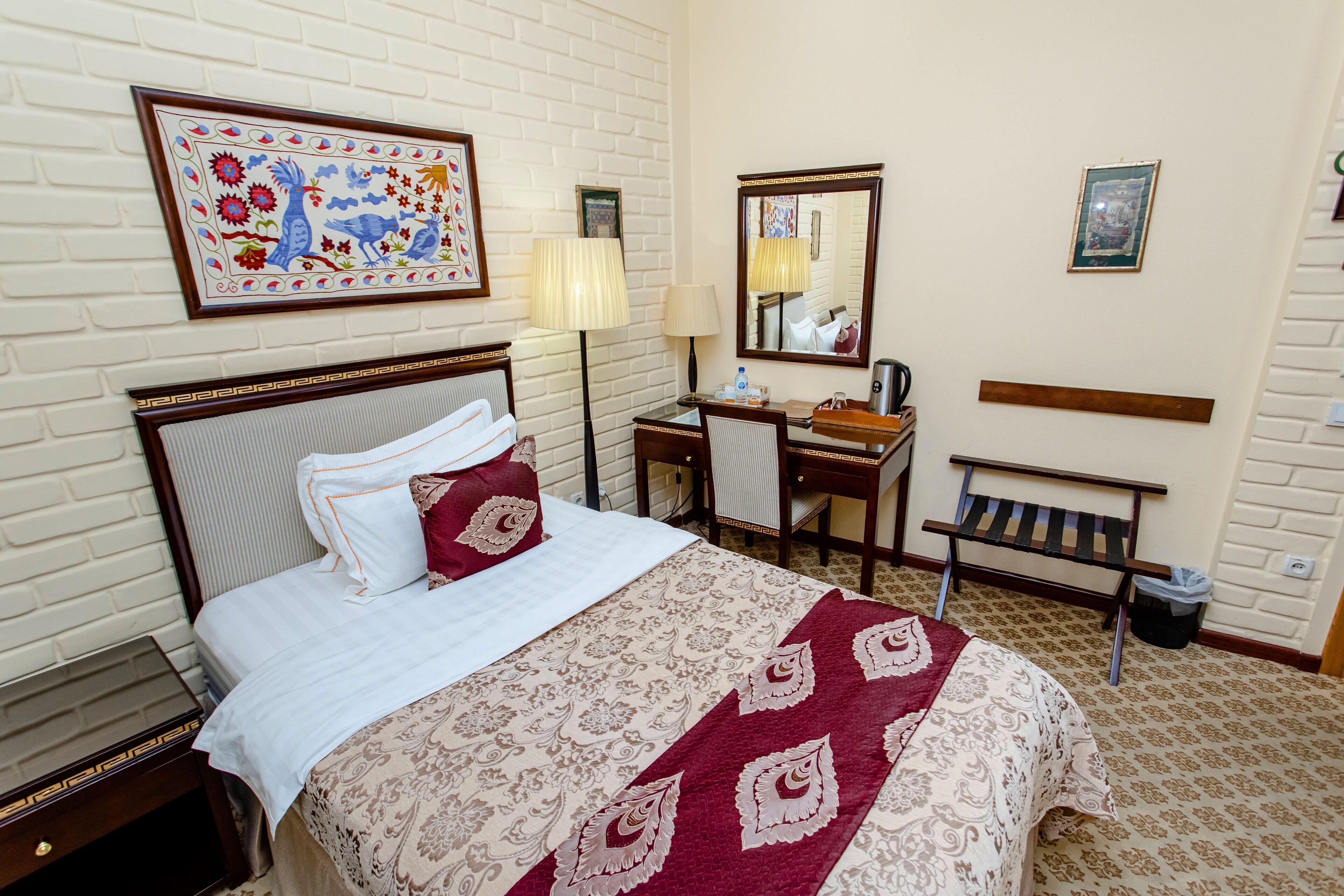 Quarto de hotel com cama, escrivaninha, cadeira e um banco.