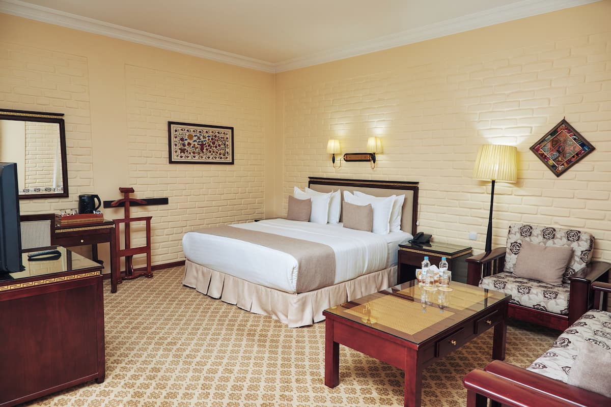 Une chambre d’hôtel avec un lit, un bureau, une chaise, une lampe et un téléviseur.