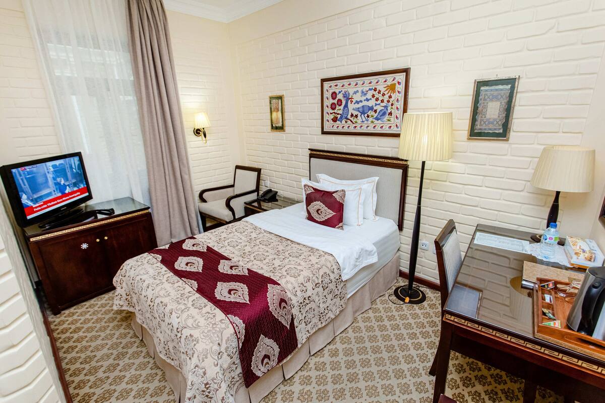 Une chambre d’hôtel avec un lit, un bureau, une chaise, une télévision et une lampe.