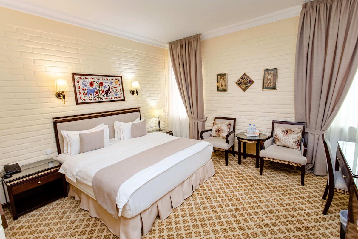 Une chambre d  ’hôtel avec un grand lit, deux chaises, une petite table et une table de chevet.