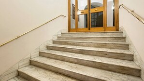 Una escalera de mármol con una puerta de madera al final, que da a un espacio interior.