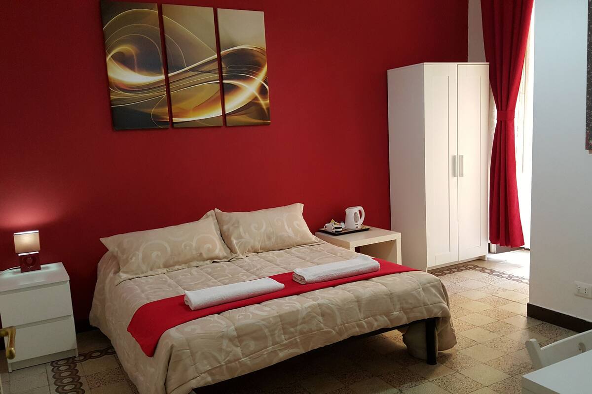 Una habitación de hotel con cama, mesita de noche, armario y un cuadro en la pared.