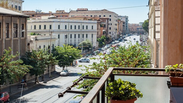 Una calle urbana con edificios, coches y un peatón.