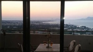 Een balkon met een tafel en stoelen, met uitzicht op een stadsgezicht en bergen in de verte.