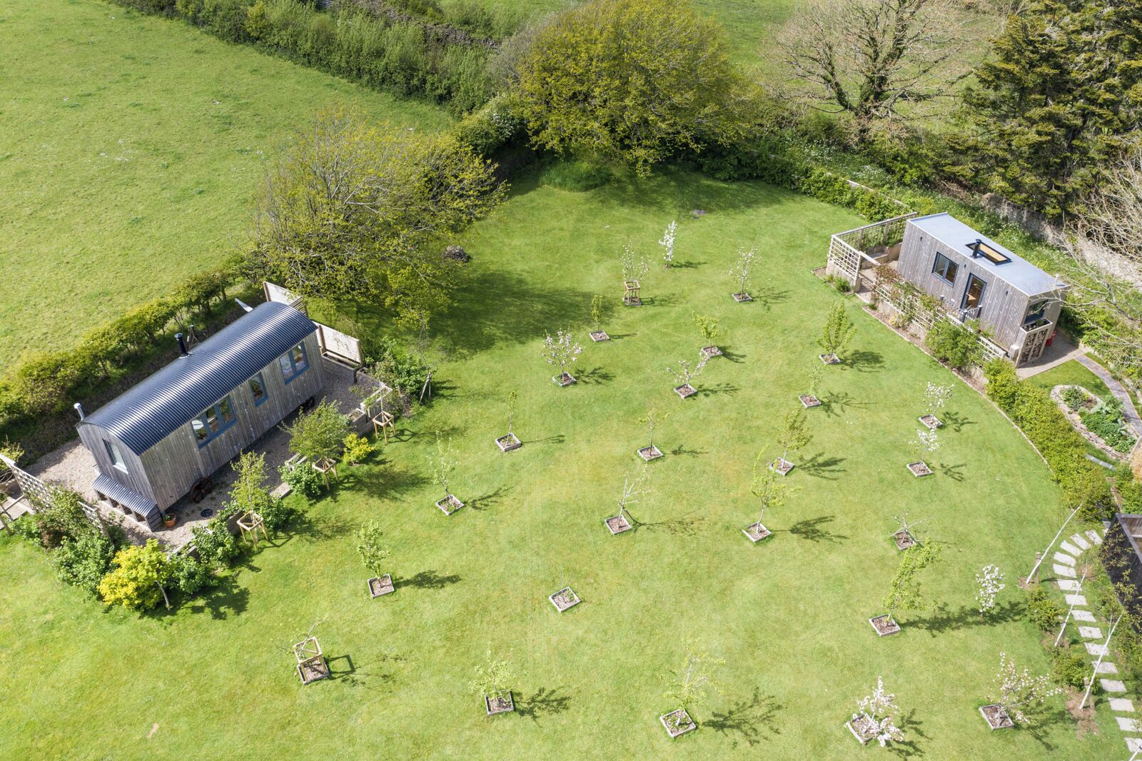 A large, open grassy area with a small building and a larger structure with a sloped roof.