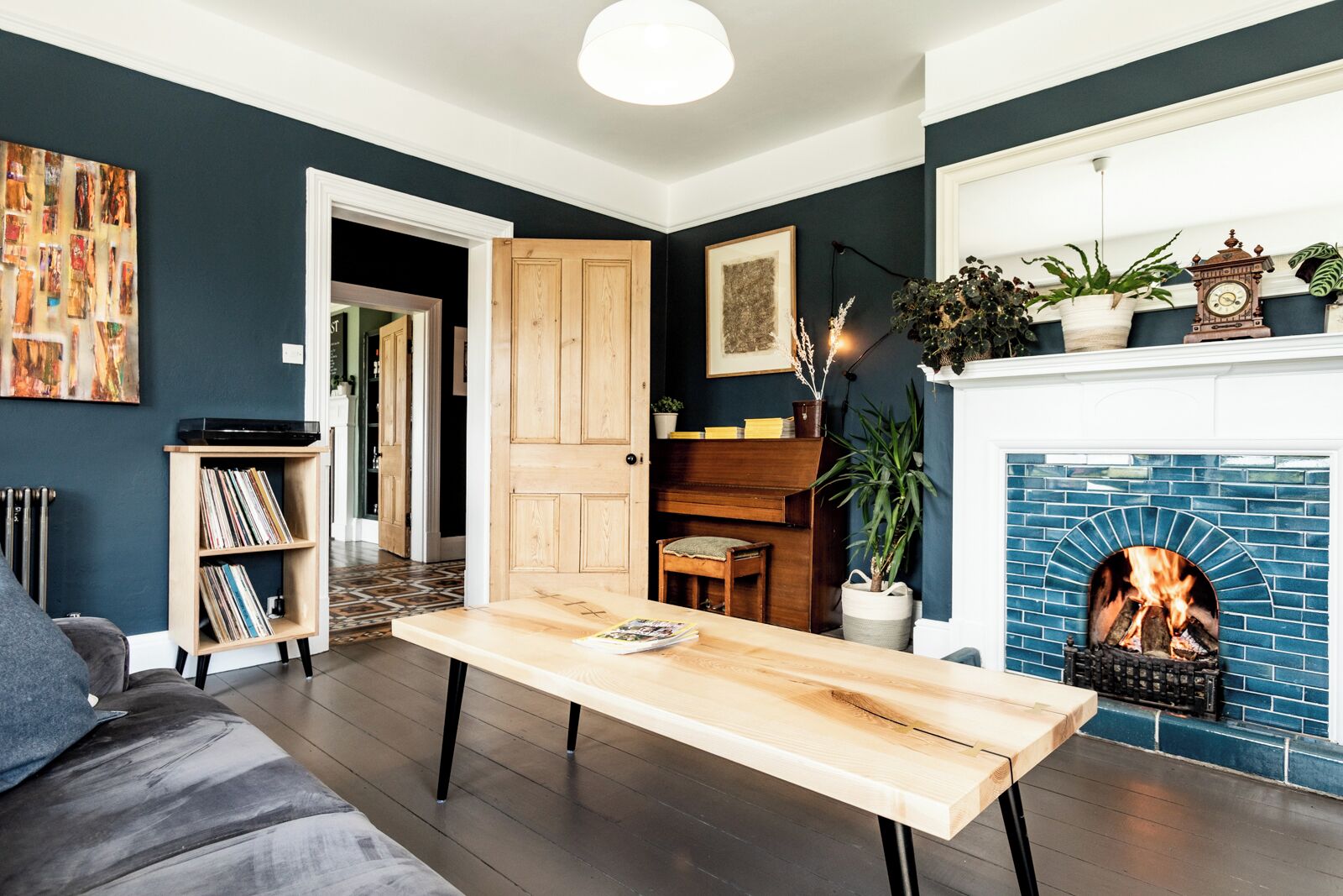 Una sala de estar con chimenea, una mesa de madera, una estantería y un sofá.