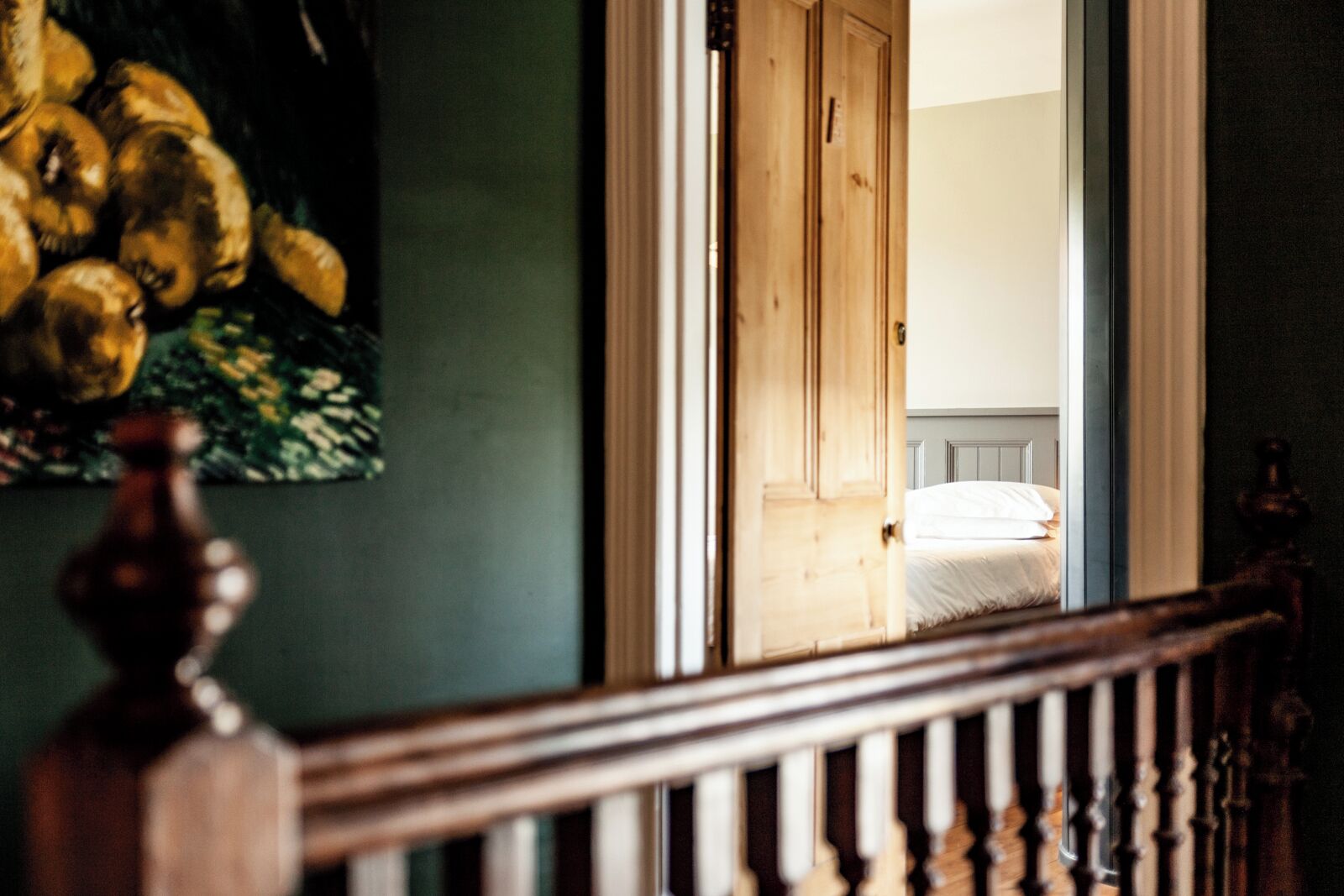 Una habitación con una cama, una puerta de madera y un cuadro en la pared.