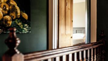 Una habitación con una cama, una puerta de madera y un cuadro en la pared.
