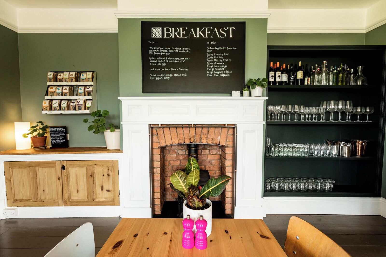 A breakfast area with a menu board, a fireplace, and a bar with various bottles.
