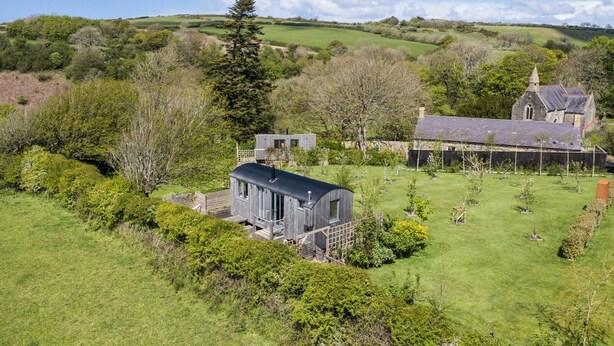 A rural landscape with a modern house, a traditional building, and a church in the background. - The Old Vicarage (Cardigan)