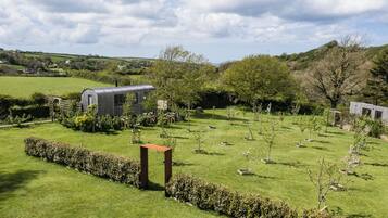 A rural landscape with a modern house surrounded by a well-maintained garden and a few trees.