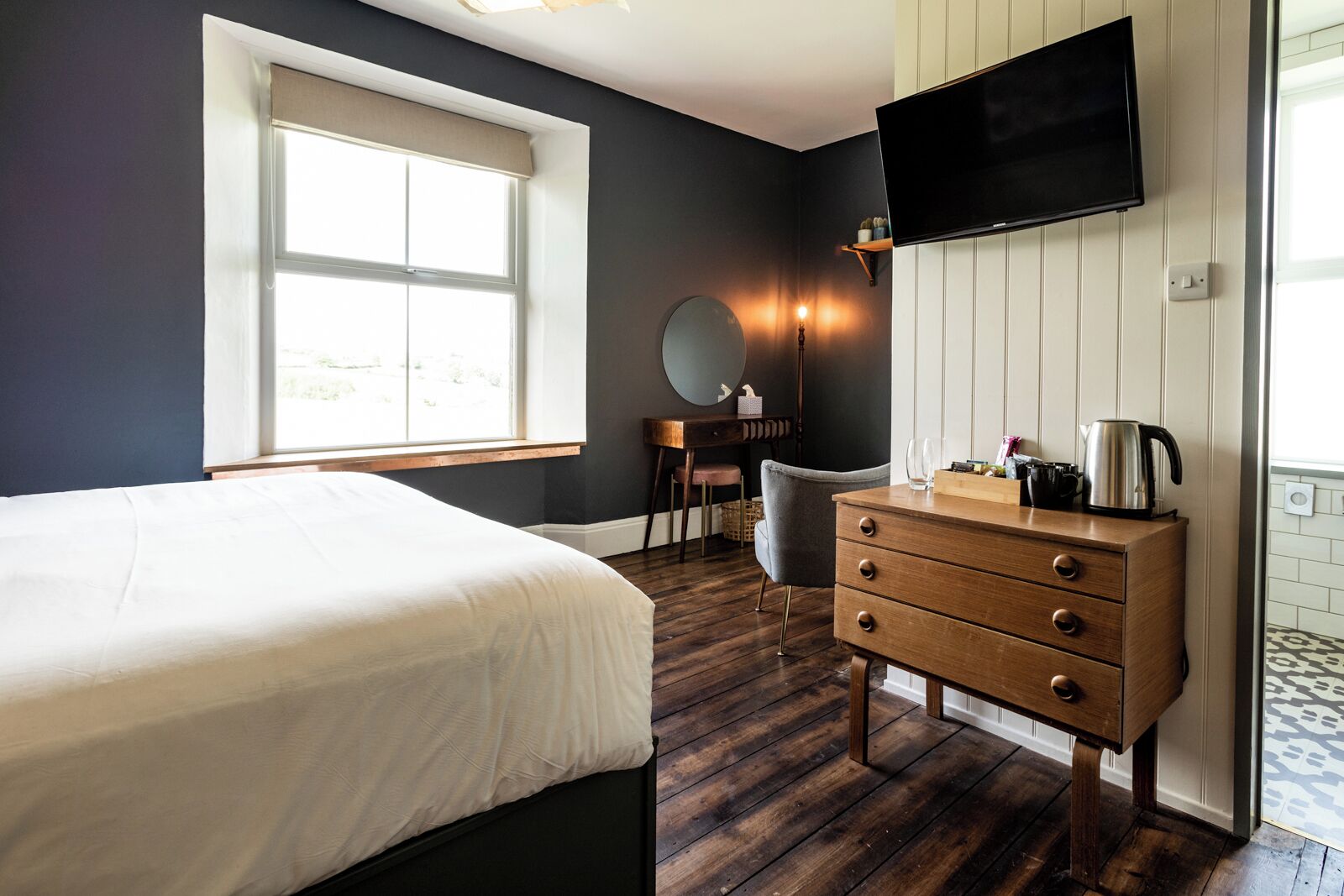Hotelkamer met een bed, een kaptafel, een aan de muur bevestigde televisie, een bureau met stoel en een raam met uitzicht.