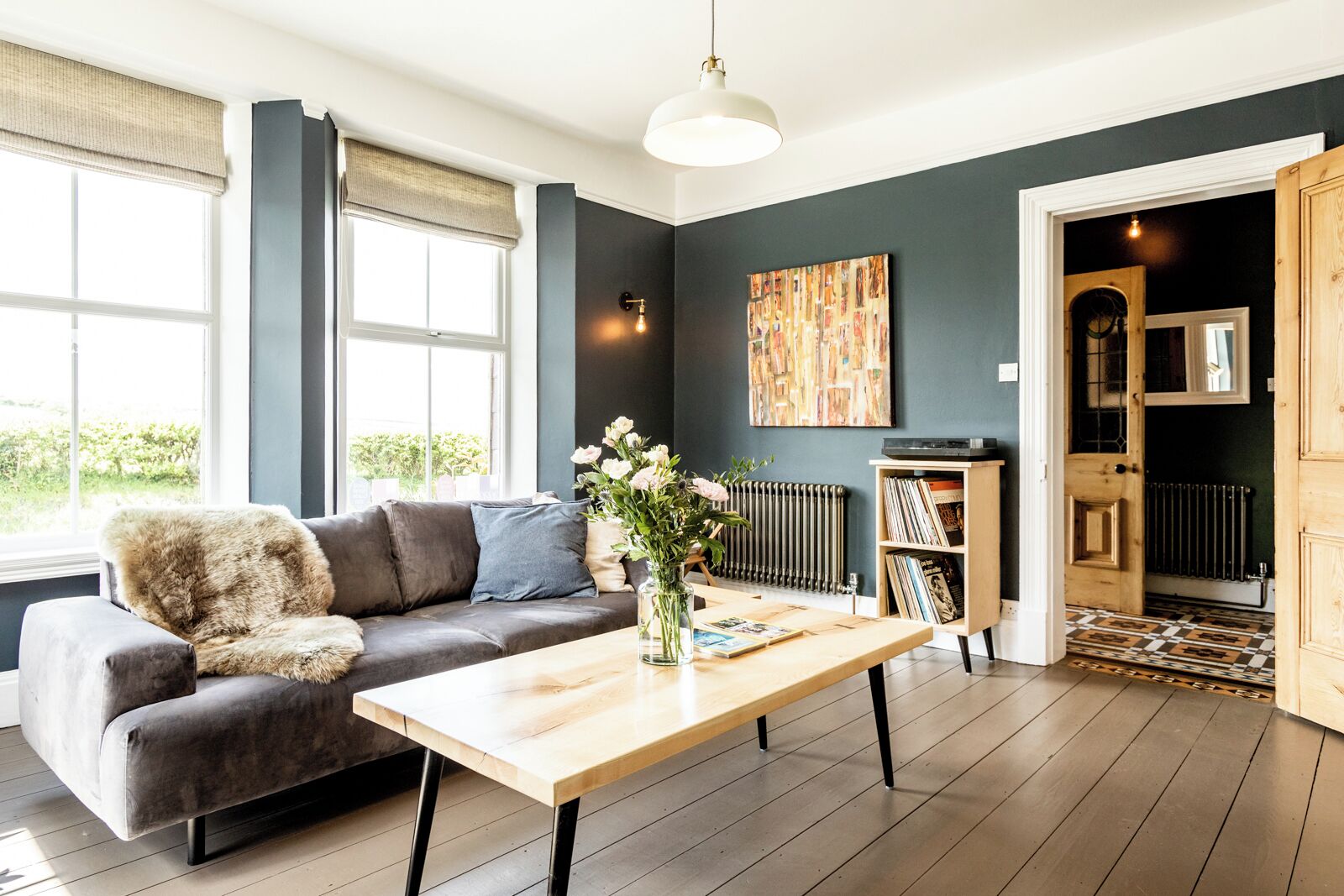 Una sala de estar moderna con un sofá gris, una mesa de centro de madera y una estantería.