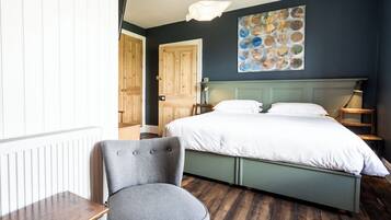 Un dormitorio con una cama, una silla, una mesa y una obra de arte colgada en la pared.