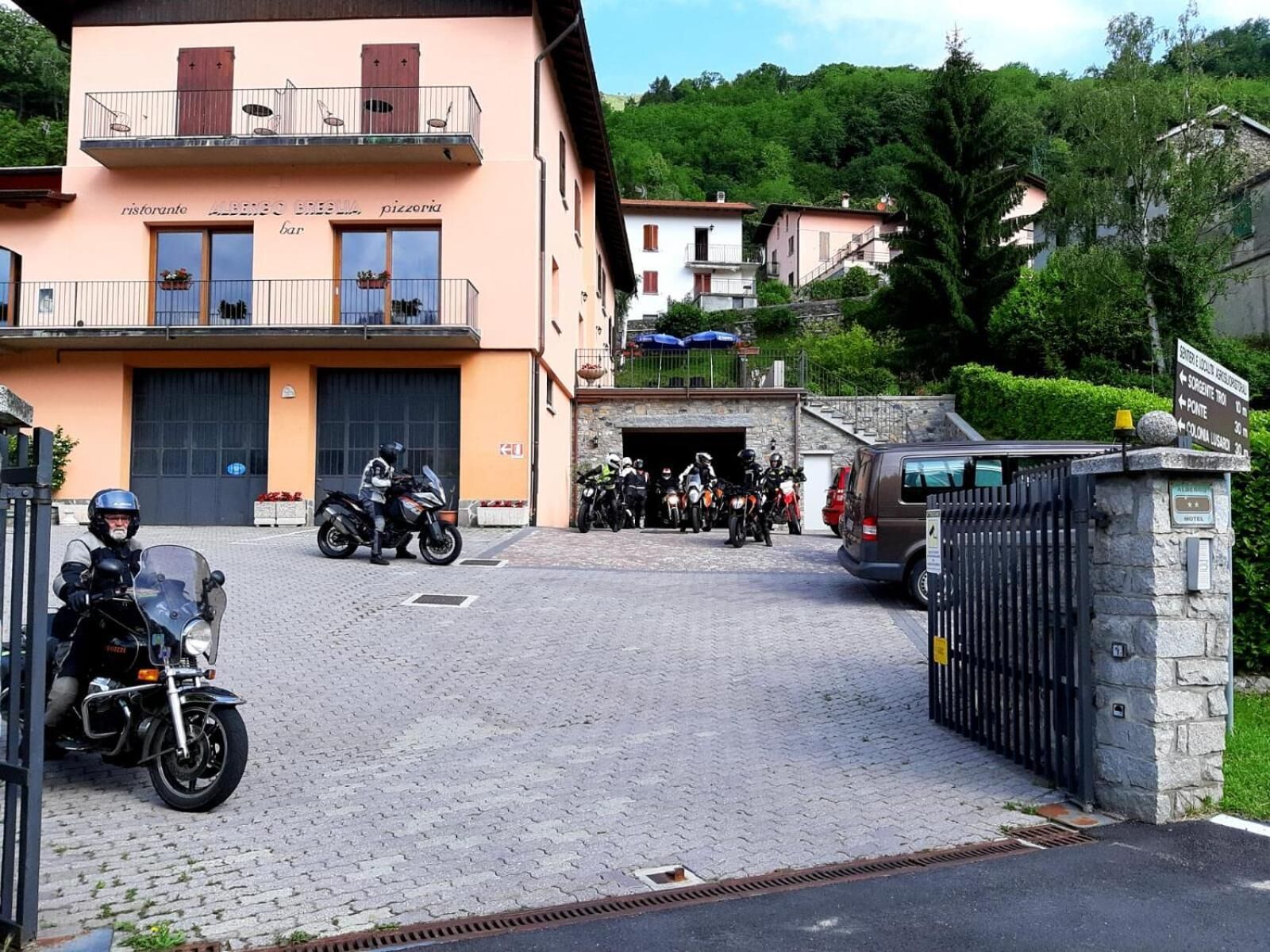 A building with a bar and restaurant on the ground floor, a garage entrance, and a stone wall with a gate.
