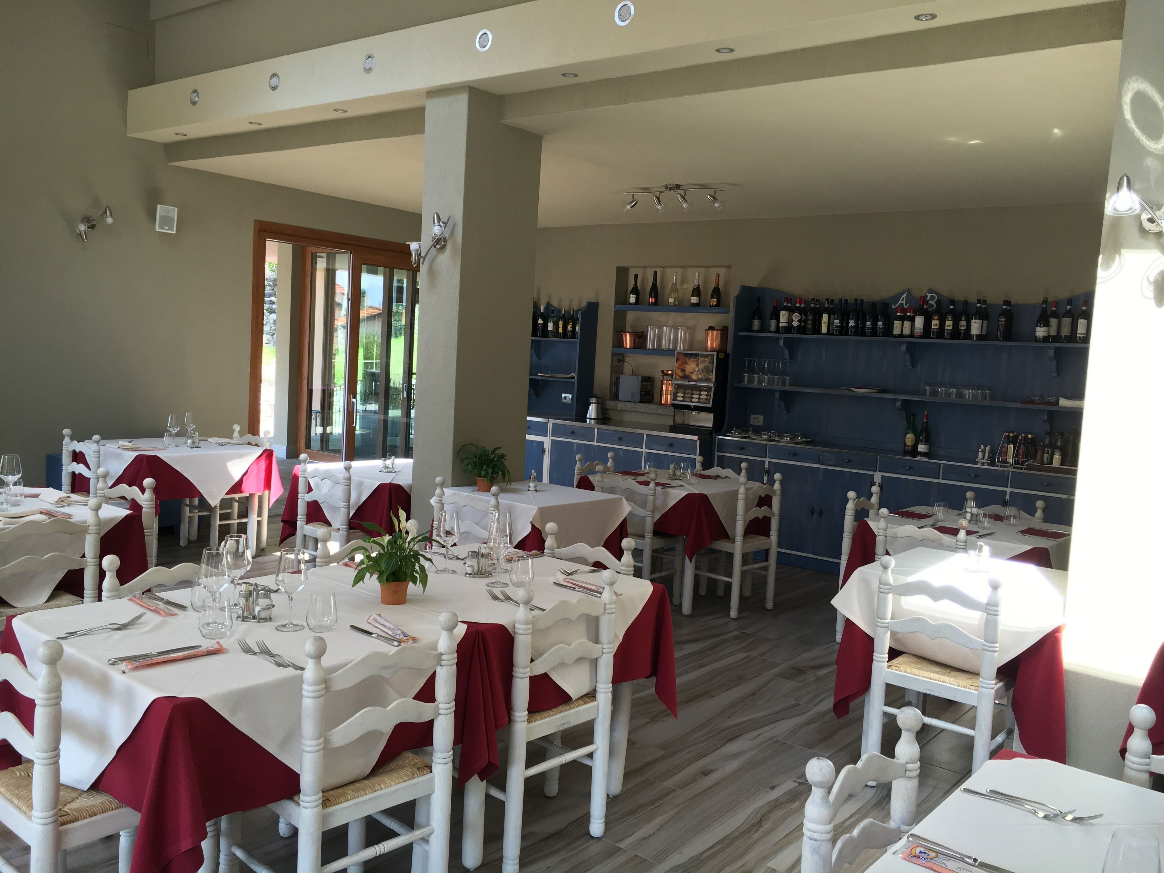 A restaurant with tables set for dining, a bar area with bottles, and a view of the outdoors.