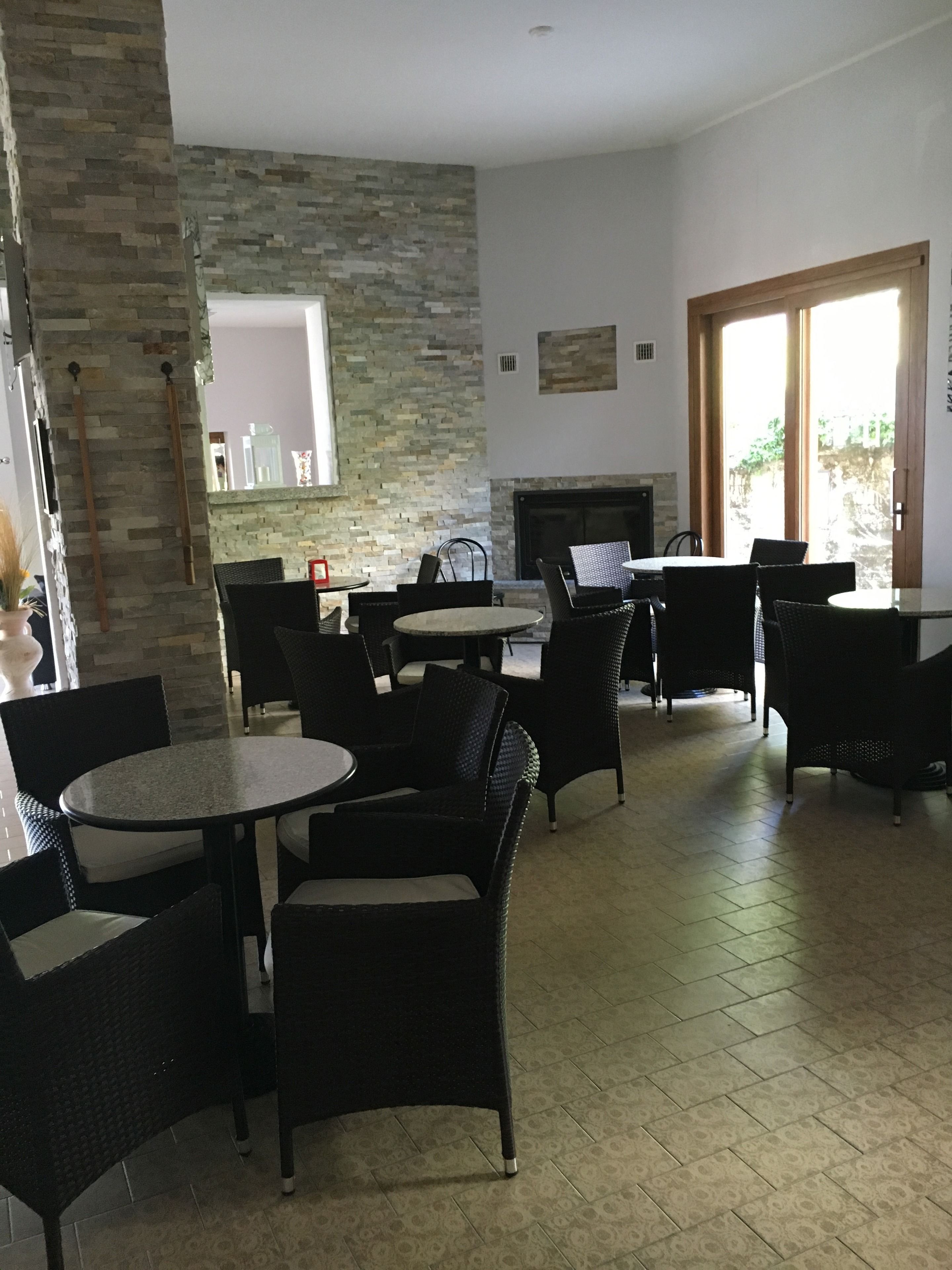 A spacious indoor seating area with stone walls, a fireplace, and large windows.