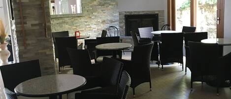 A spacious indoor seating area with stone walls, a fireplace, and large windows.