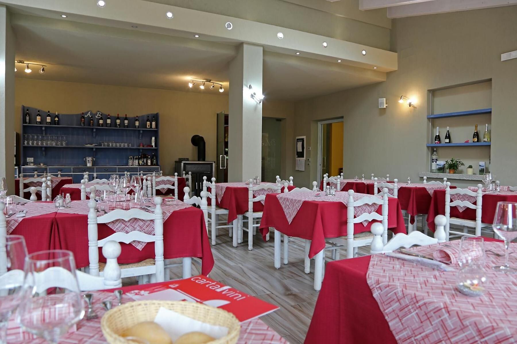 Ein Restaurant mit mehreren Esstischen, einer Weinauslage und einem Barbereich.