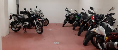 Eine Reihe von Motorrädern steht in einem Raum mit rotem Boden und weißen Wänden.