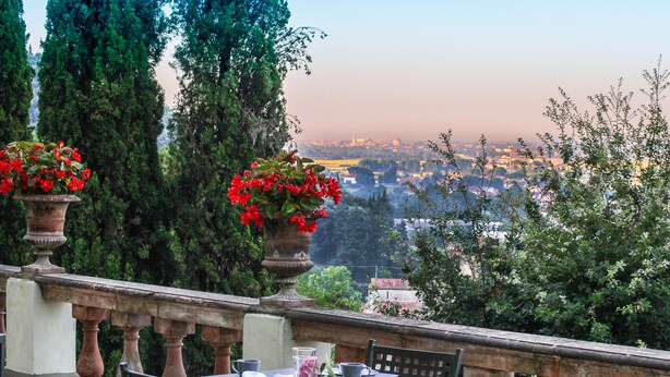 A terrace with a table set for dining, overlooking a cityscape. - Villa Alta (San Giuliano Terme)