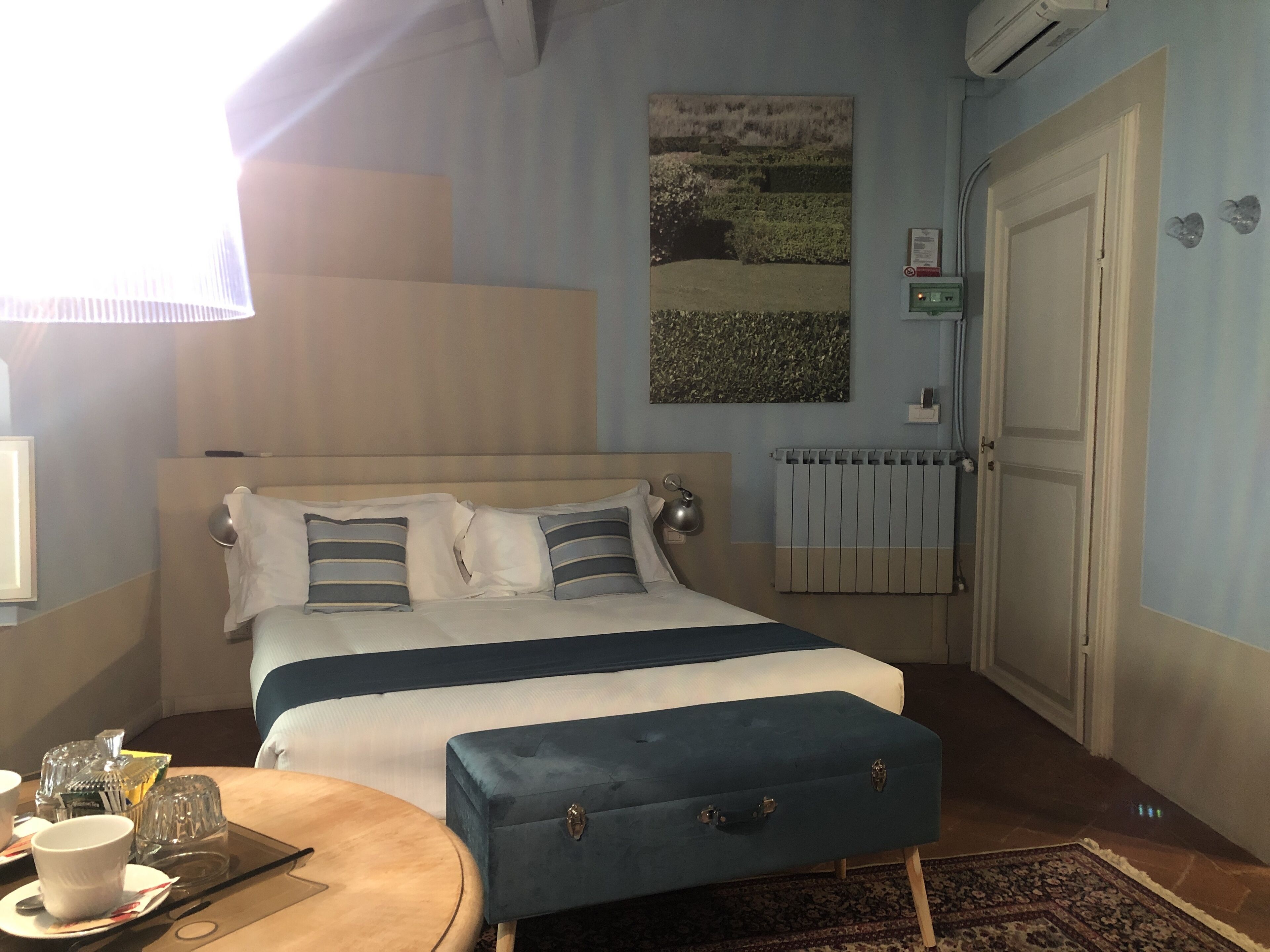 A neatly arranged bedroom with a bed, bedside table, and a small ottoman.