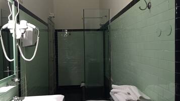 Un baño con lavamanos, inodoro y ducha con mampara de vidrio.