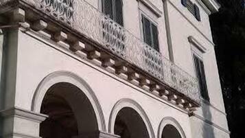 Ein Gebäude im klassischen Stil mit einem Balkon, der kunstvoll gestaltete Brüstungen und eine Reihe von Bögen aufweist, die die Struktur tragen.