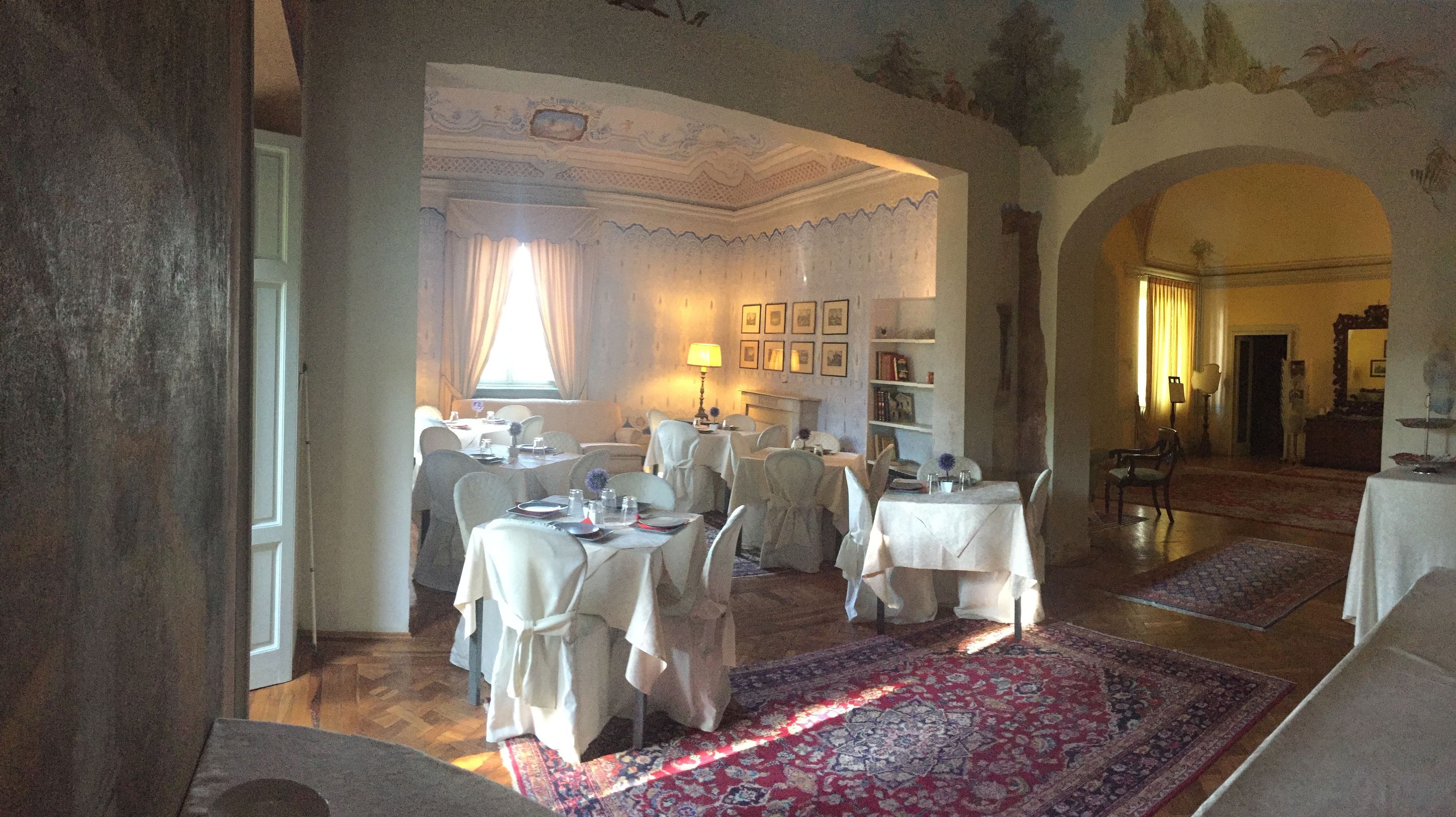 Un espace repas avec des tables dressées pour le repas, un lustre et une cheminée.