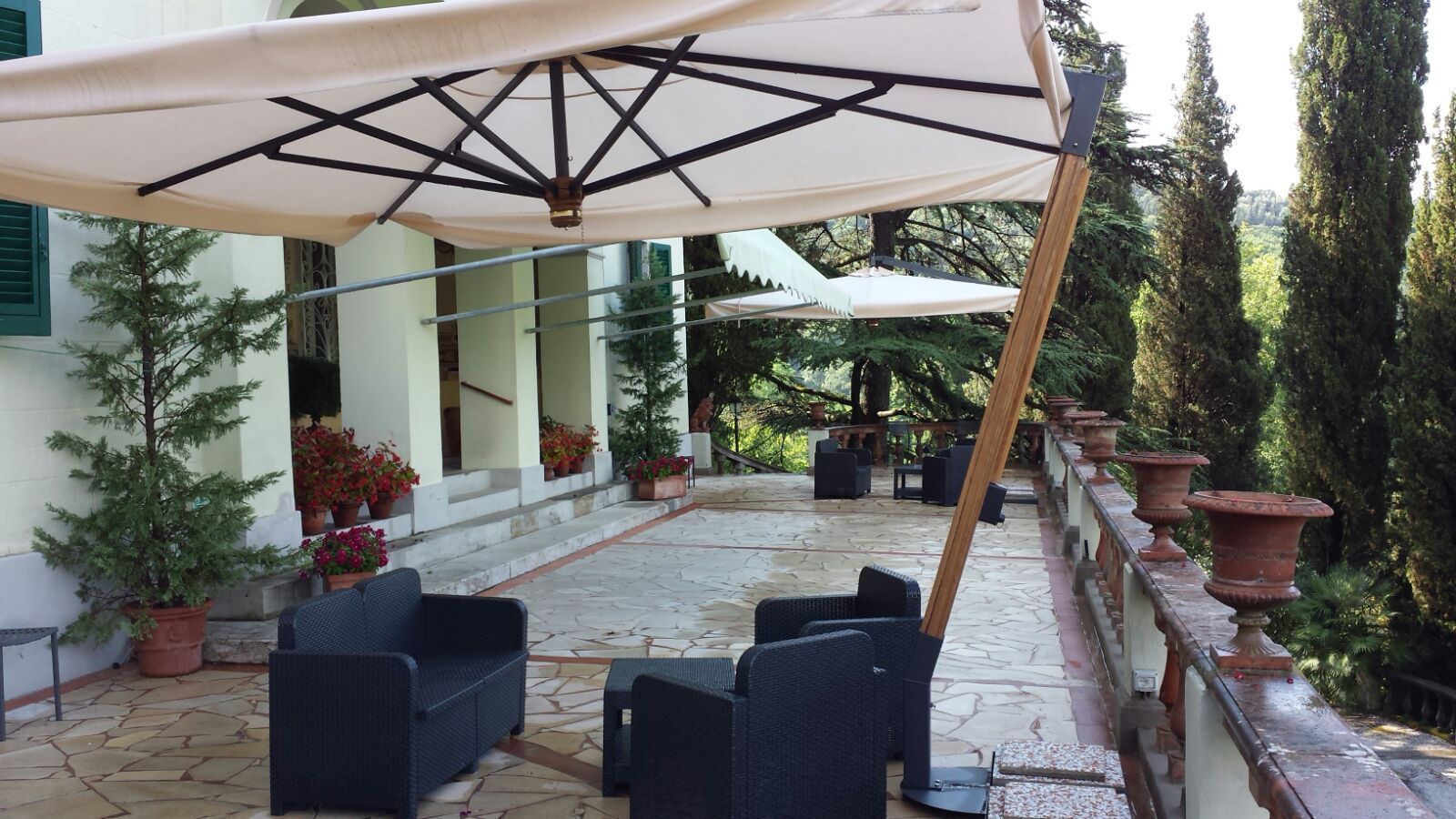 Eine Terrasse im Freien mit Korbmöbeln und einem großen Sonnenschirm.