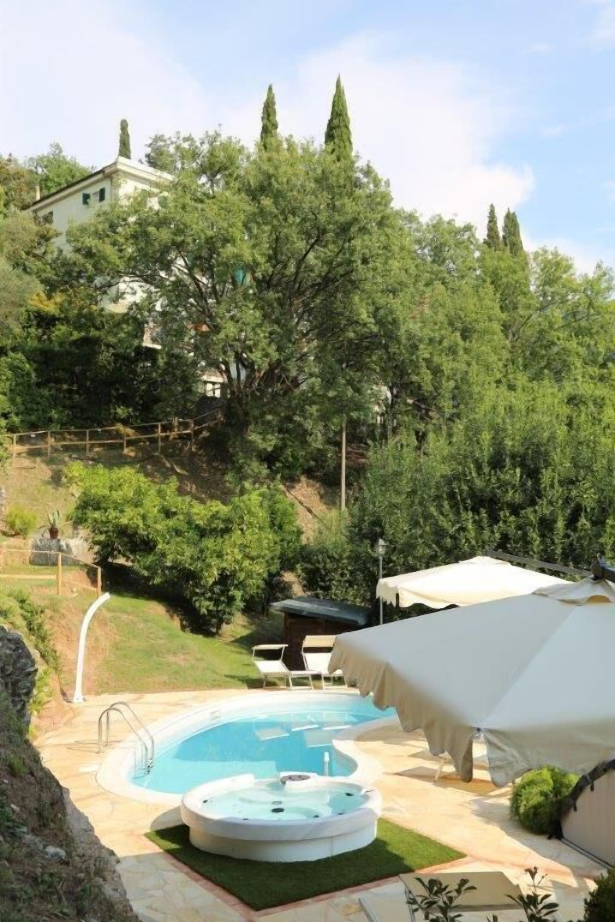 Un patio trasero con piscina, jacuzzi y un área de terraza techada.