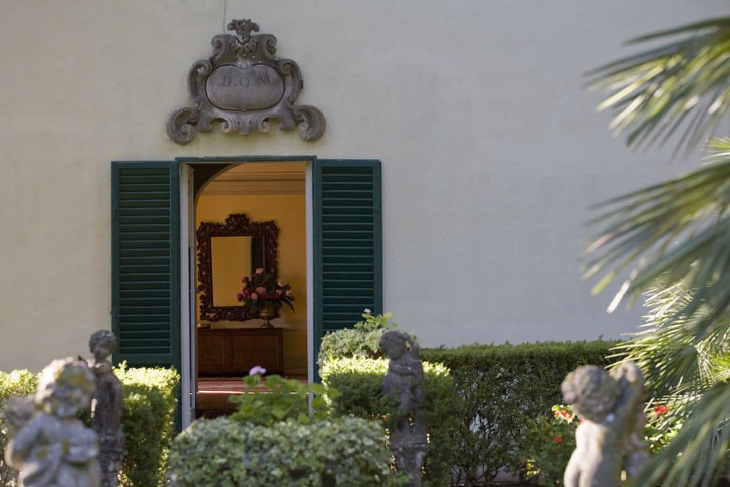 Une entrée d'immeuble agrémentée d'une enseigne décorative, d'un miroir et de statues au premier plan.