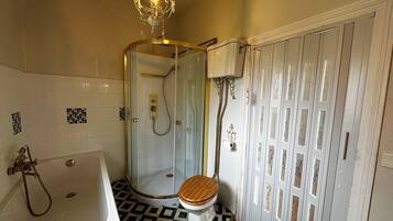 A bathroom with a bathtub, a glass-enclosed shower, and a toilet.