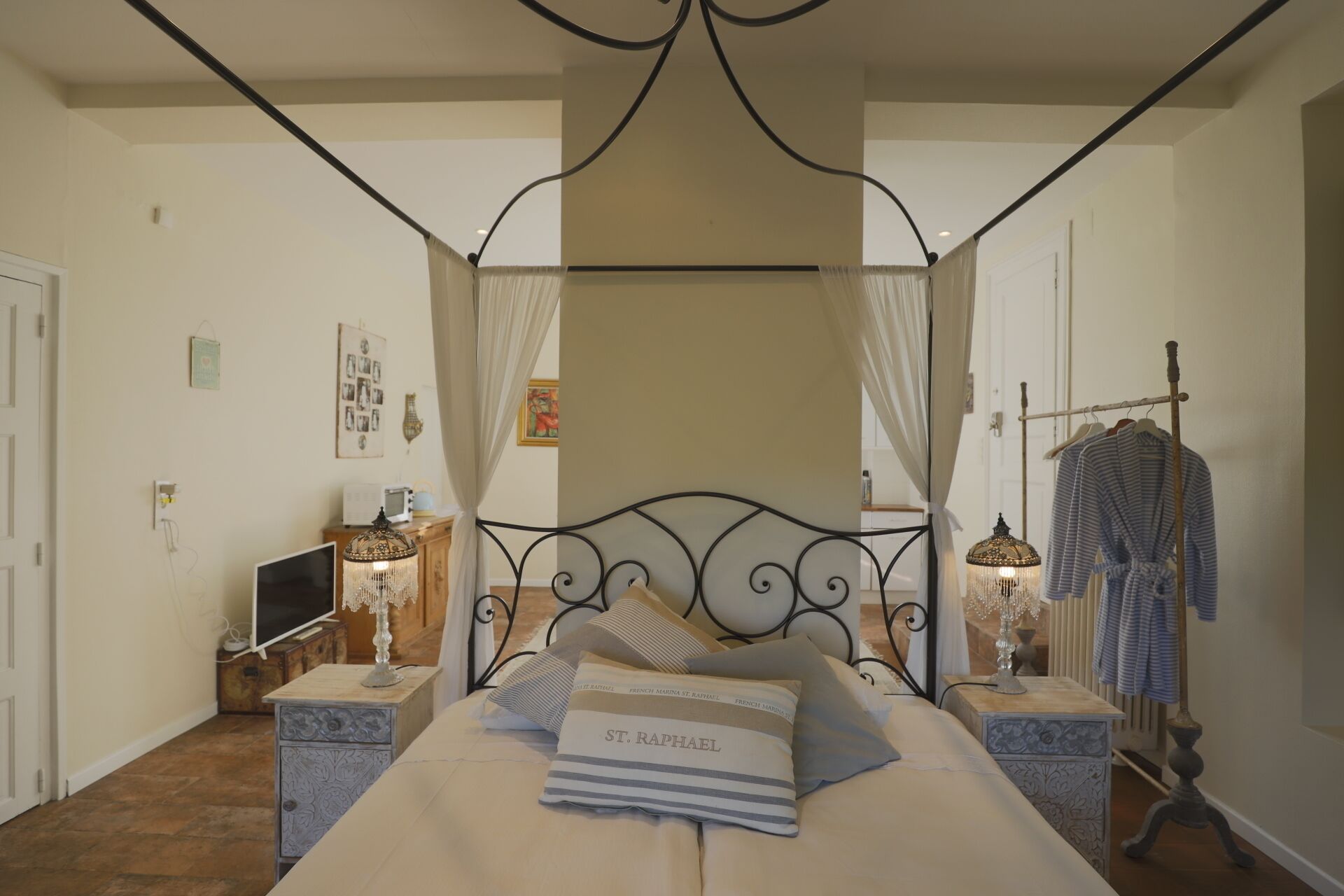 A bedroom with a four-poster bed, bedside tables, a TV, and a wardrobe.
