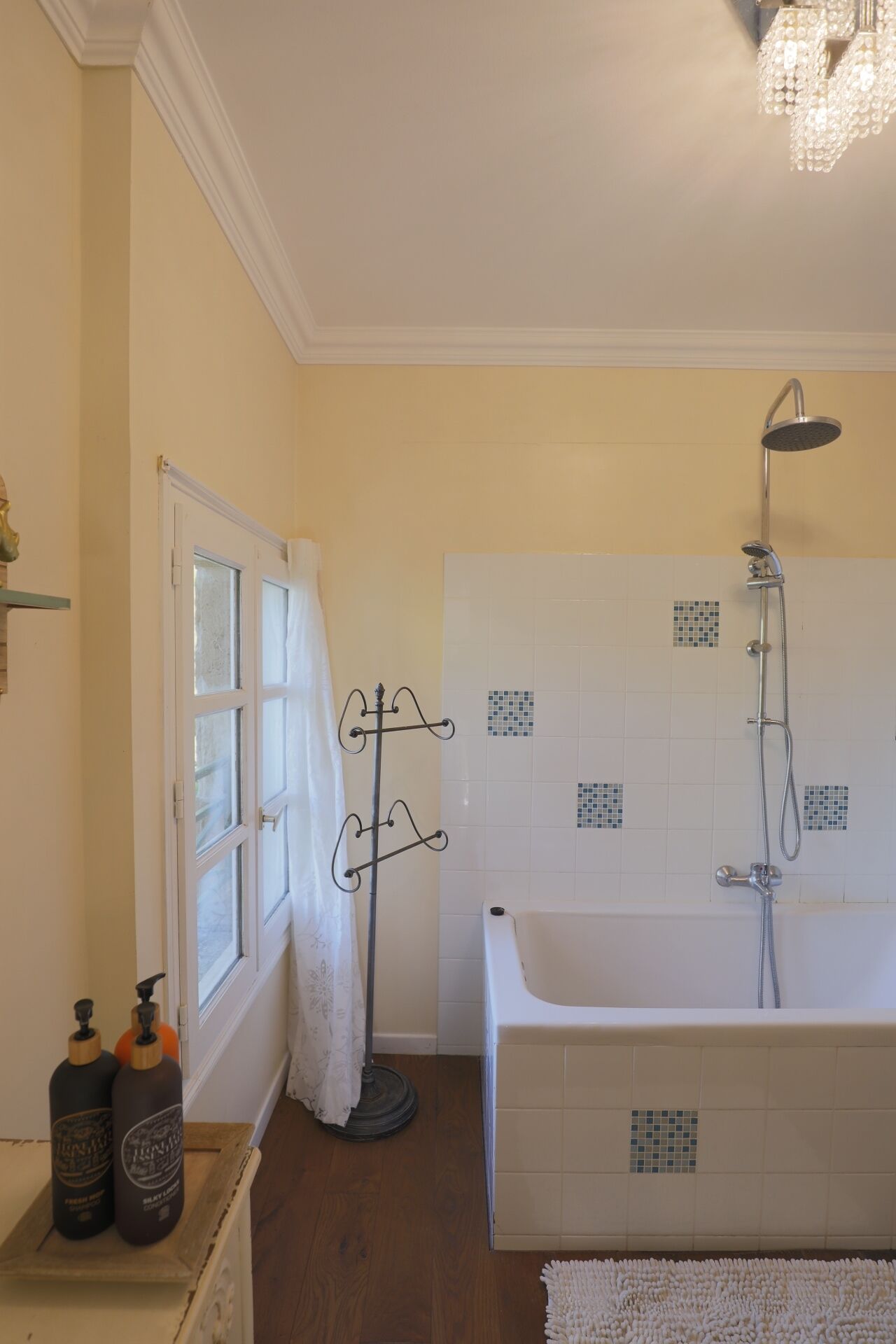 Un baño con bañera, ducha y ventana con cortina.