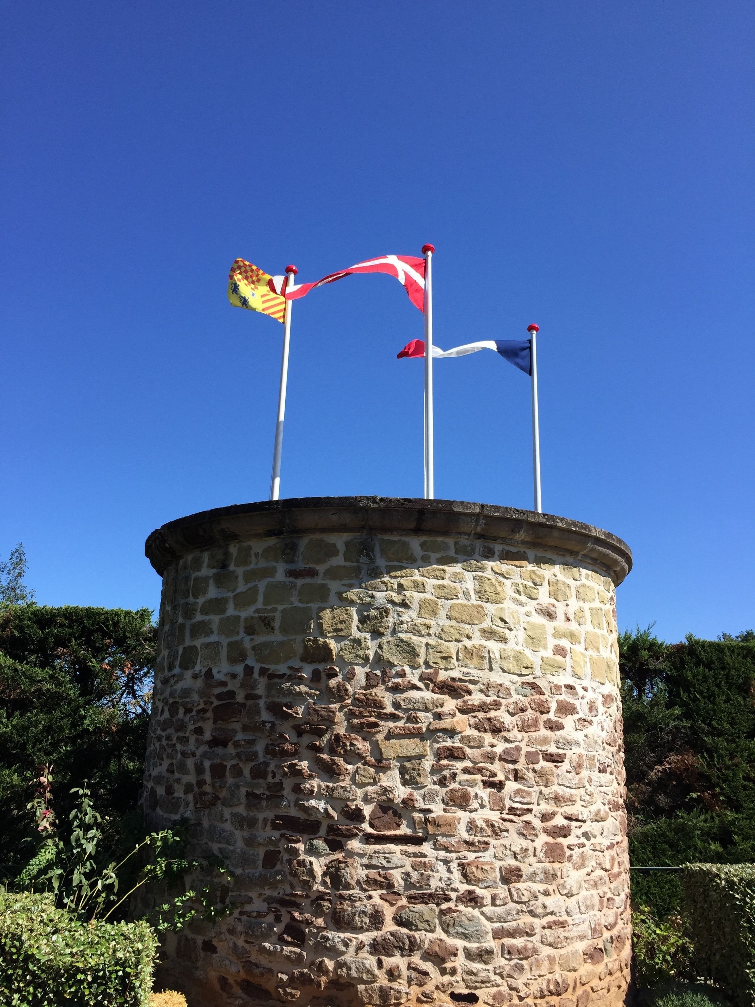 Een stenen toren met drie vlaggen erop.